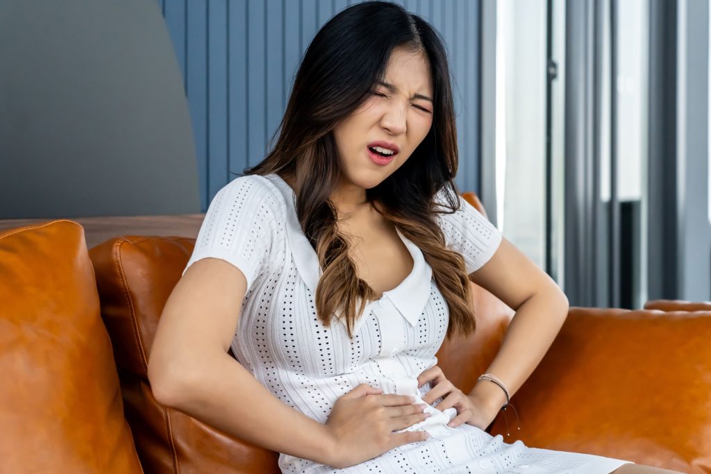 TCC_Blog_202408_Menstrual-Cramps_young_lady_sitting_on_couch_having_lower_abdominal_pain_mensturation_discomfort